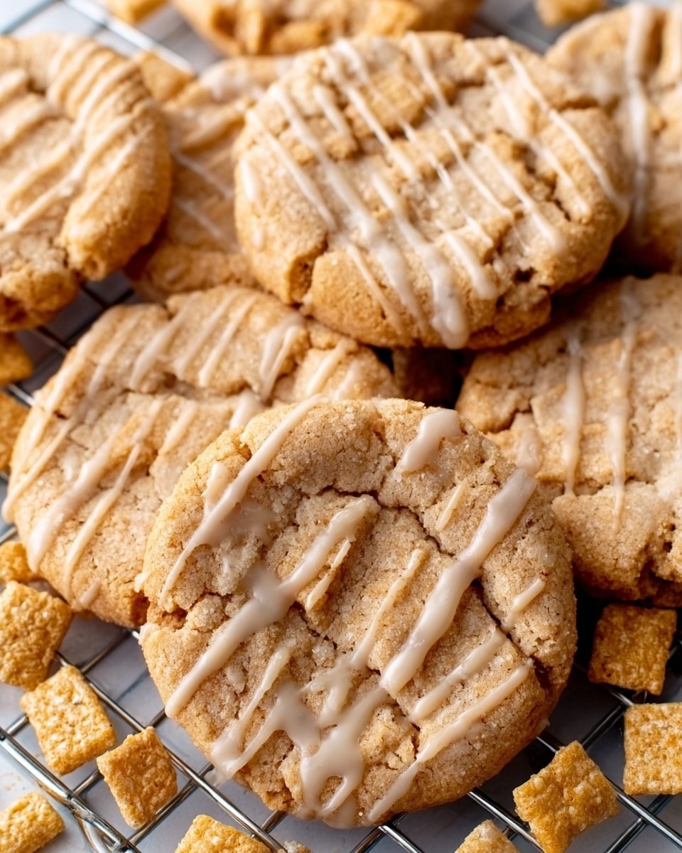 The image shows a close-up of several soft peanut butter cookies with a light tan color and slightly cracked tops, each cookie has a thin white glaze drizzled in horizontal lines across the surface, the cookies are placed on a cooling rack over a white marbled surface, some small square cereal pieces in light golden brown are scattered around the cookies. Photo taken with an iphone --ar 4:5 --v 7