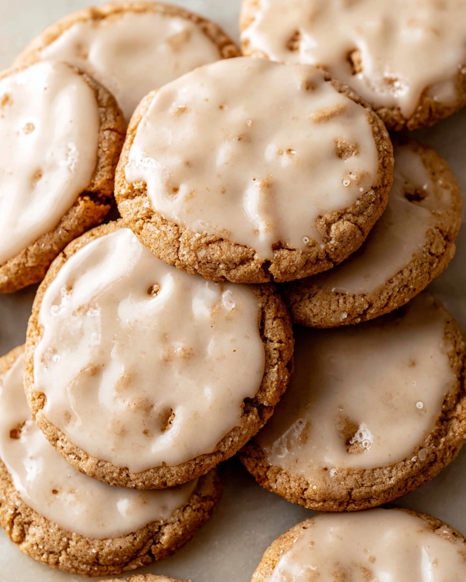 A close-up view of several round cookies stacked unevenly on a white marbled surface, each cookie has a light brown base with a textured, slightly rough surface and is topped with a smooth, creamy light beige glaze that spreads unevenly, showing some thin cracks and bubbles. The glaze contrasts softly with the cookie base, and the cookies overlap in a casual pile, creating a cozy, warm feeling. photo taken with an iphone --ar 4:5 --v 7