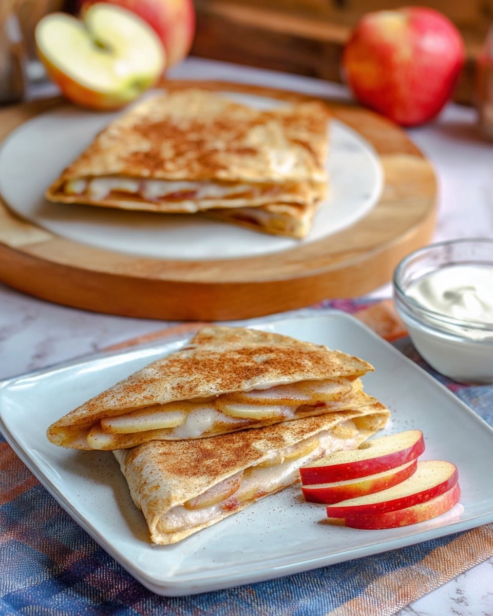 The image shows two triangular quesadilla slices on a white square plate, each slice composed of two golden brown tortillas with a visible layer of thin apple slices and a creamy white filling peeking from the edges. Next to the quesadilla slices, there are a few fresh apple wedges with red skin and pale yellow flesh. In the background, there are two folded quesadillas on a round wooden cutting board, showing a rich golden brown color with a sprinkle of cinnamon or sugar on top, and inside, bright red apple slices can be seen. Behind the board, a halved apple and a clear bowl of white creamy dip are placed on a white marbled surface. The whole setting has warm and soft natural lighting. photo taken with an iphone --ar 4:5 --v 7