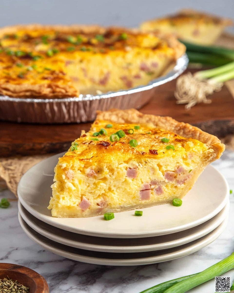 A slice of quiche sits on a stack of white plates, showing three visible layers: a light golden-brown flaky crust at the bottom, a thick middle layer of creamy yellow egg mixed with pink pieces of ham, and a top layer that is slightly browned and bubbly with melted cheese. Bright green chopped scallions are scattered on top, adding freshness and color contrast. In the background, the full quiche is visible in a silver foil pan, with a similar golden top and green garnishes, set on a wooden board. The setting includes a few green onions lying on the white marbled surface and a small wooden bowl with dried herbs nearby. photo taken with an iphone --ar 4:5 --v 7