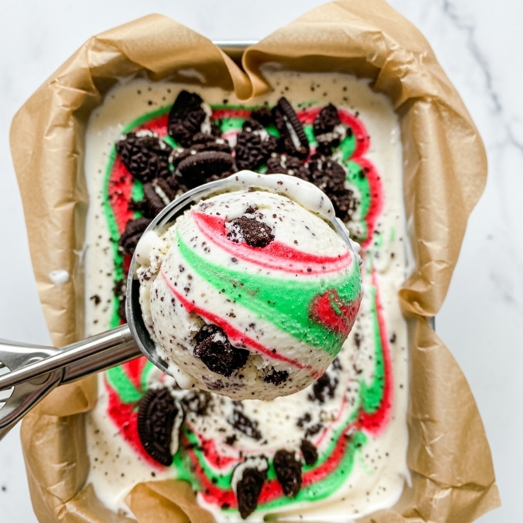 The image shows a close-up of a scoop of creamy ice cream held by a metal ice cream scooper. The ice cream is white with a smooth texture, mixed with dark brown cookie chunks and swirls of bright red and green, giving a festive look. The ice cream is in a tin lined with brown parchment paper, and the background has a white marbled texture. The ice cream looks rich and slightly soft, with cookie pieces spread throughout the tub. photo taken with an iphone --ar 4:5 --v 7
