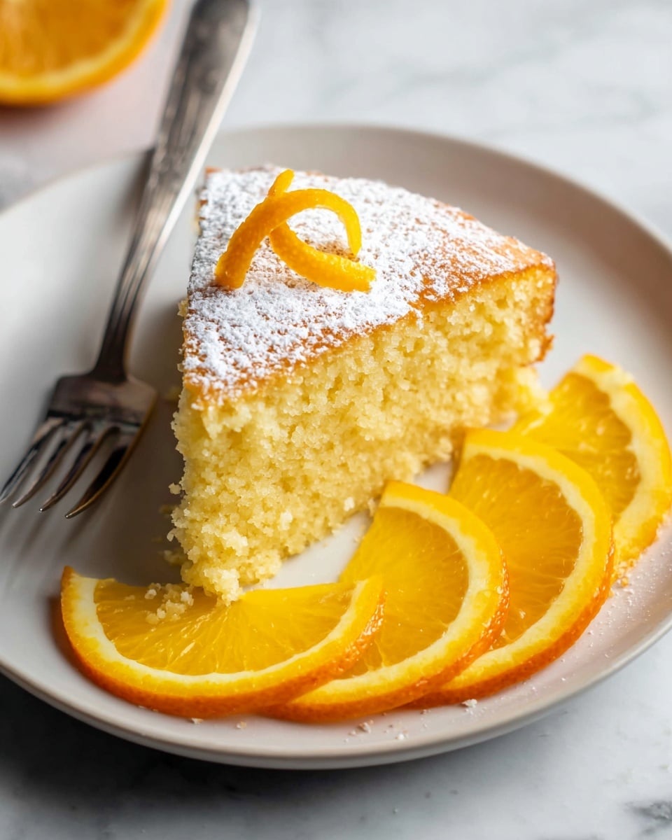 A round, single-layer lemon cake with a golden yellow top dusted evenly with powdered sugar, cut into twelve diamond-shaped slices and placed on a black wire cooling rack over a white marbled surface. On the cake's top right, two thin orange slices and one lemon slice are stacked. To the left of the cake, there is a small white bowl filled with powdered sugar and a wooden-handled knife with a silver blade resting on the surface near a half lemon. A metal spatula with a wooden handle is sliding under one cake slice at the bottom right. A dark gray cloth is partly visible beneath the cooling rack. Photo taken with an iphone --ar 4:5 --v 7