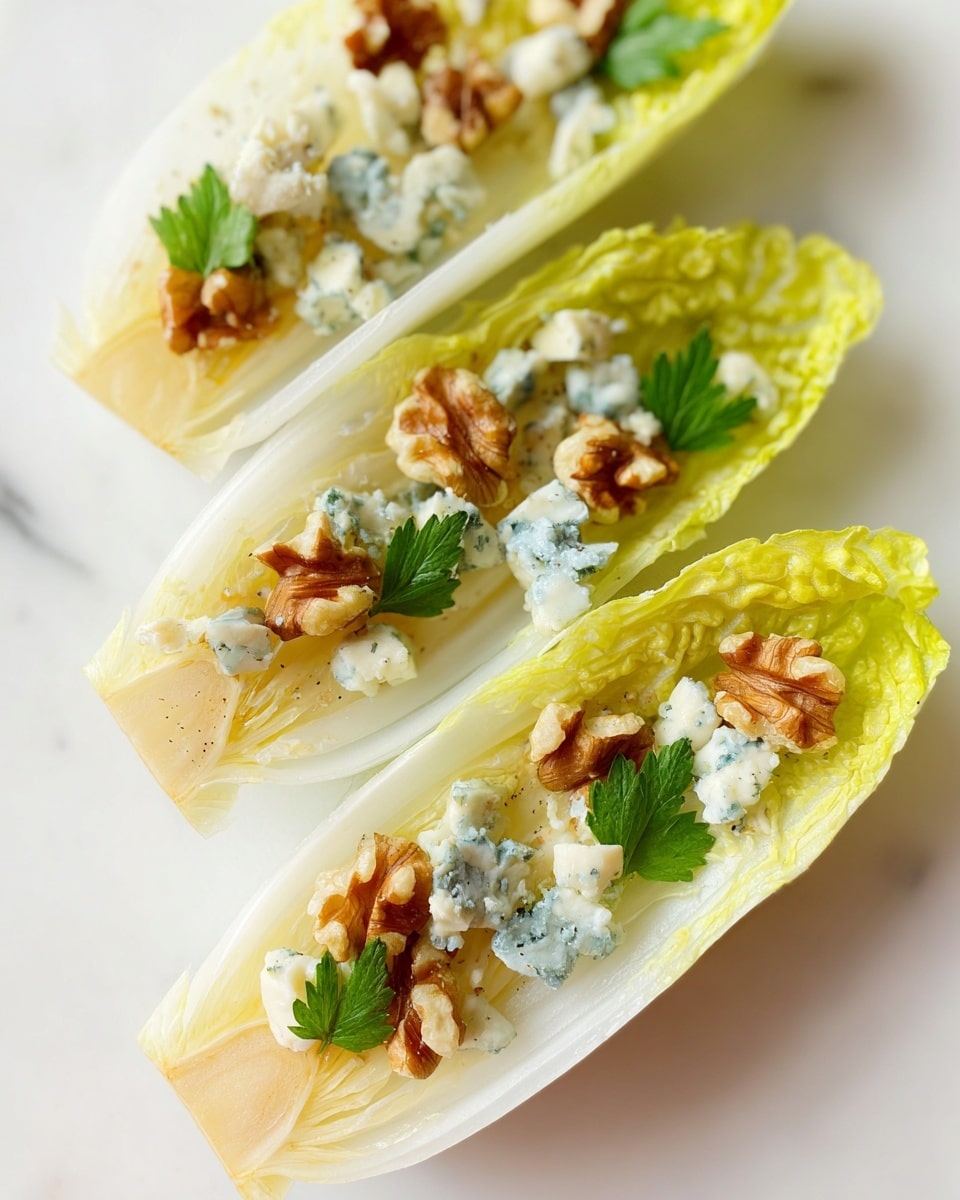 The image shows three endive leaves arranged in a close-up view on a white marbled surface. Each pale yellow leaf serves as a boat-shaped base, holding small green parsley leaves, crumbled blue cheese pieces with white and sky-blue spots, and golden-brown walnut halves, all evenly scattered on top. The textures range from the smooth and slightly glossy surface of the endive to the crumbly cheese and the rough, wrinkled walnut pieces, creating a fresh and crisp appetizer look. photo taken with an iphone --ar 4:5 --v 7